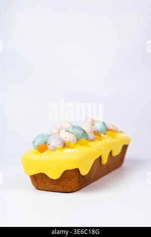 Easter loaf cake with yellow icing and candy eggs isolated Stock Photo