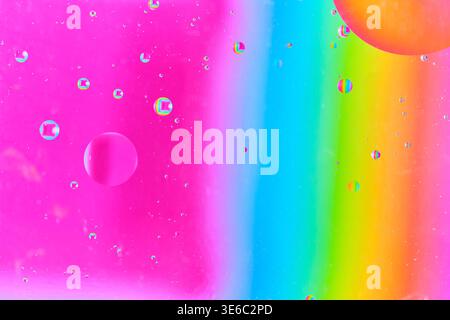 Dispersed oil droplets creating bokeh effect over bright magenta and cyan vertical gradient Stock Photo