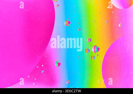 Dynamic liquid abstract with small rainbow tinted bubbles floating in pink and yellow gradient Stock Photo