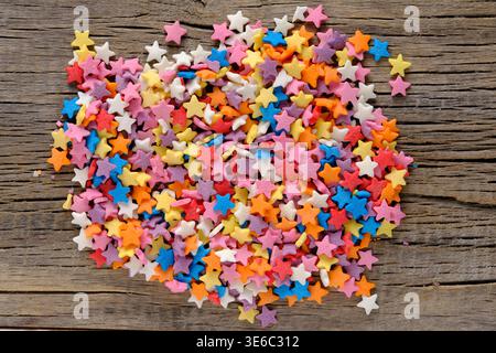 Vibrant heap multi colored sugar stars featuring pink, orange, blue, and yellow hues on dark wooden surface Stock Photo