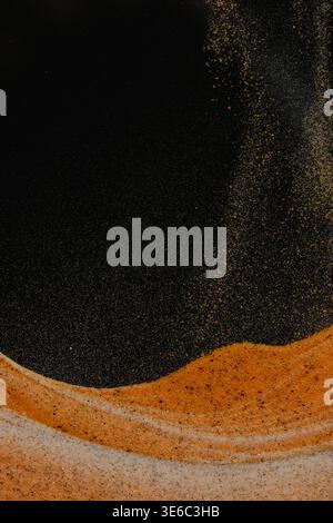 Fine sand grains swirling in air like stars above curved orange dune in total darkness Stock Photo