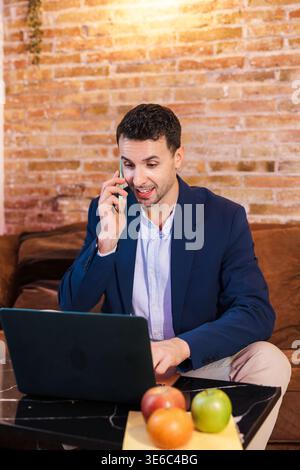 Businessman working on laptop and talking on phone in cafe Stock Photo