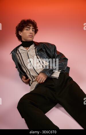 Handsome man relaxes in fashionable attire with a striking background of colors. Stock Photo