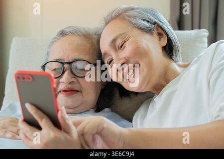 Smiling senior mother and adult daughter sharing a joyful moment on their smartphone. Family, Happiness, and Connection Theme. Stock Photo