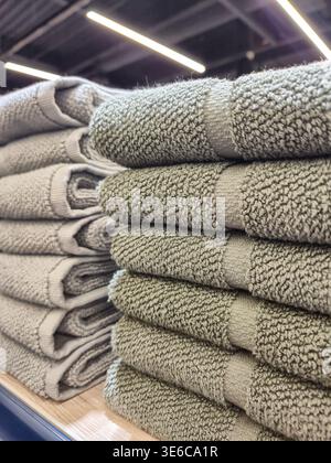 A close up view showcases stacks of soft, textured bath towels arranged on a wooden shelf, ready for use Stock Photo