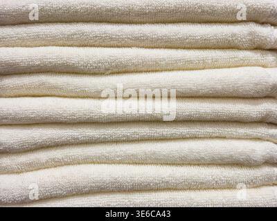 Soft, fluffy white towels neatly stacked in a clean, organized pile Stock Photo
