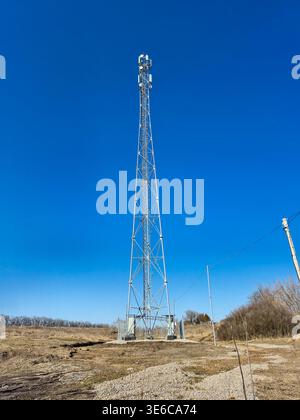 Tall cellular tower transmitting signals against a clear blue sky Stock Photo