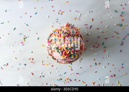 A top down view of a scoop of strawberry ice cream, topped with rainbow sprinkles. Stock Photo