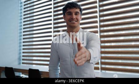 Portrait happy friendly Caucasian business man holding hand in front greeting handshaking offer gesture businessman hold arm handshake welcome male Stock Photo