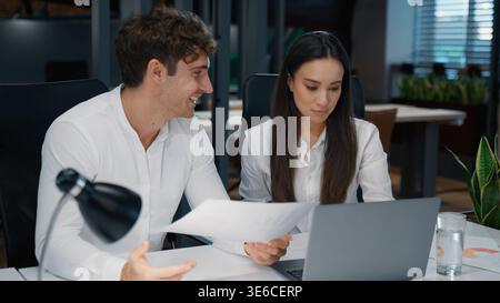 Two business colleagues talking research papers analyzing documents discussion work result in office businesswoman with businessman talk working Stock Photo