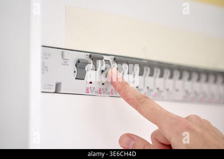 Hand switching circuit breaker in electrical distribution panel. Concept of power control, electrical safety, household utility and energy management. Stock Photo