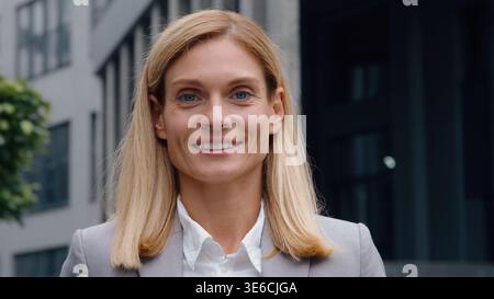 Caucasian middle-aged business woman looking at camera smile portrait close-up happy inspired businesswoman joyful smiling female posing in downtown Stock Photo