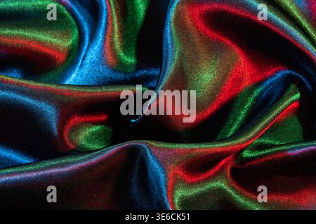 Iridescent satin fabric reflects red, green, and blue light creating an abstract pattern Stock Photo