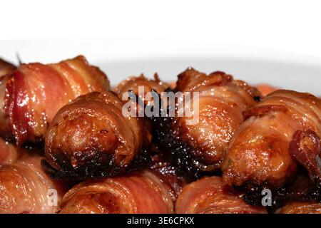 Close up of chipolatas pigs in blankets sausages wrapped in bacon on white background Stock Photo