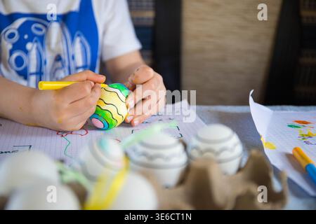 Caucasian child painting plastic Easter eggs, craft and art activity spring idea for kids. Stock Photo