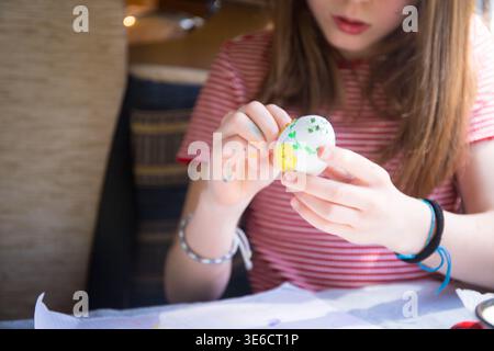 Caucasian child girl painting plastic Easter eggs, craft and art activity spring idea for kids. Stock Photo