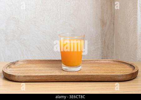 A rustic, blown-glass tumbler holds peach and apricot juice, with a sprig of fresh mint emerging from the translucent liquid Stock Photo