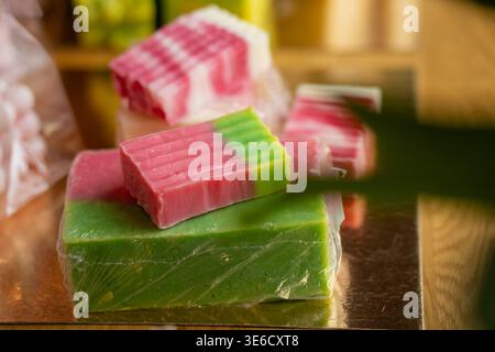 Assorted handmade soap bars in vibrant pink and green colors displayed on a gold surface, featuring artisanal layered patterns for organic skincare an Stock Photo