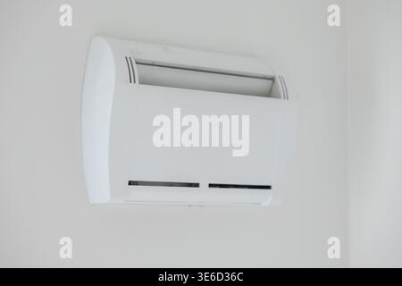 Sleek white air conditioning unit mounted on a pristine wall, ensuring energy-efficient climate control and comfortable temperature regulation for any Stock Photo