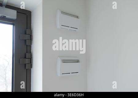 Contemporary design of two white ventilation systems installed on a sleek wall next to a modern door, emphasizing interior climate regulation and arch Stock Photo