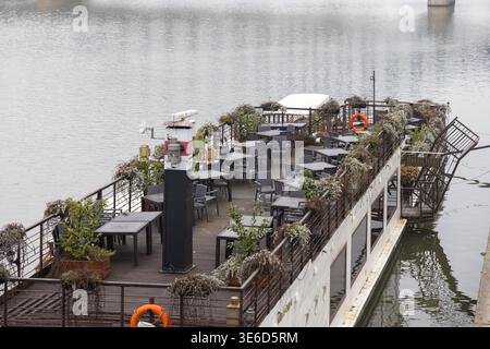 Krakow, Poland - December 2, 2025: A serene view of an unoccupied boat restaurant's outdoor seating area featuring multiple tables and chairs arranged Stock Photo