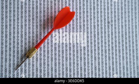 Red dart hitting binary code background depicting targeted data attacks and digital precision. Stock Photo