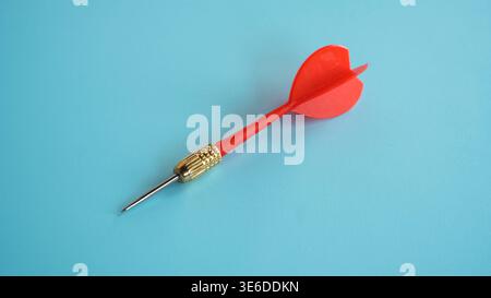 Single red dart on blue background representing goal setting and business strategy. Stock Photo