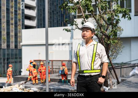 A civil engineer stands confidently overseeing construction workers in the background. The image reflects leadership, awareness, and commitment to pro Stock Photo