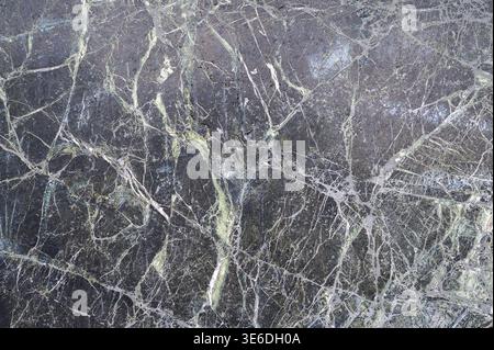 Dark natural stone with intricate white and green veining, abstract texture background Stock Photo