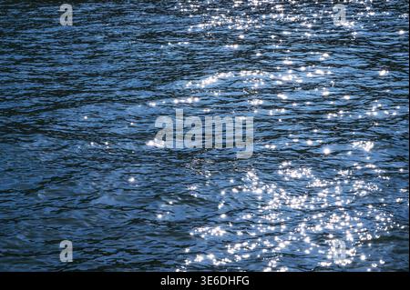 Sparkling blue water surface with sunlight reflecting on gentle ripples Stock Photo