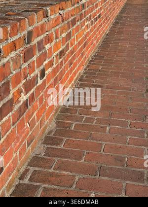 Close view of red brick wall and paved walkway at Malbork Castle in Poland showing texture and pattern in sunlight. Architecture, texture and construc Stock Photo