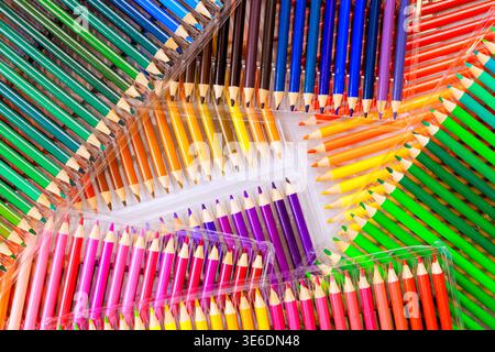 Colored pencils of different colors are placed in neat rows on light surface ready for art projects. Stock Photo