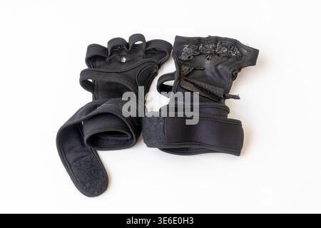 Close-up of a pair of old and torn black gym gloves isolated on a white background. Ideal for fitness equipment replacement, weightlifting fatigue, an Stock Photo