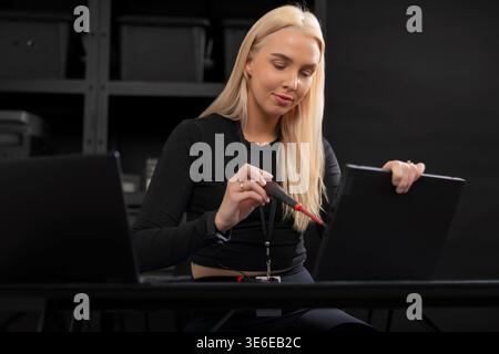 Female IT technician, young adult Caucasian, repairing a laptop with precision at a desk Stock Photo