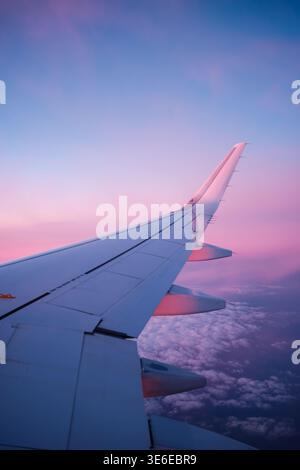 Airplane wing during sunset above clouds Stock Photo