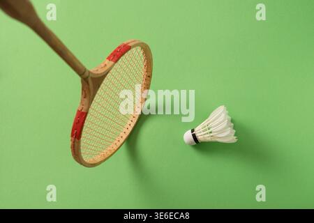 Vintage wooden badminton racket and shuttlecock on green background. Concept of sport heritage, training and active lifestyle. Stock Photo