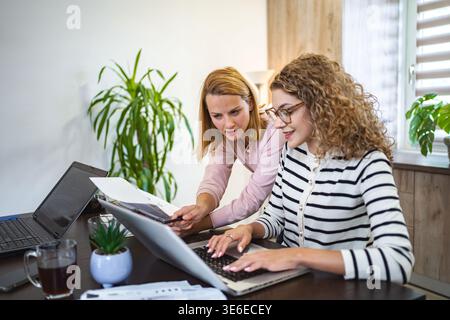 Two female colleagues working together on business report Stock Photo
