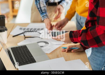 Teamwork brainstorm. Unrecognizable diverse colleagues working together discuss financial statistics. Group of people in creative office discussing business, focus on hands close up. Professional team Stock Photo