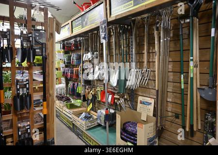 Inside garden centre with hanging racks of garden tools on sale, UK Stock Photo