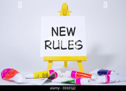 New rules symbol. Concept word Manage stress on wooden blocks. Beautiful yellow background with paints and easel. Business and New rules concept. Copy Stock Photo