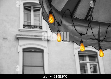 Vintage Edison bulbs illuminate a building facade with selective color Stock Photo