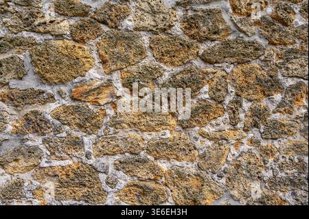 Rough textured stone wall with visible mortar and weathered surfaces Stock Photo