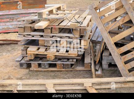 Old wooden pallets at a construction site. Used stacked wooden pallets used for storing building materials, logistics, and transporting goods at indus Stock Photo