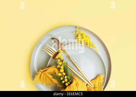 Mothers day table decor with mimosa branch and ceramic plates Stock Photo