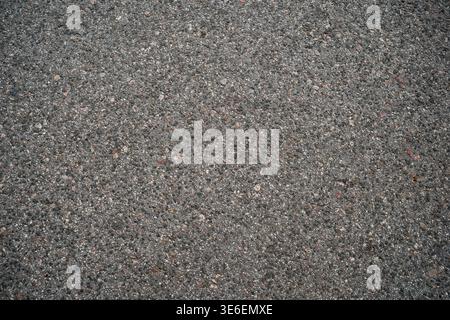 Detailed close up of rough asphalt surface with small stones and grainy texture. Neutral gray road background for design, construction, industry, and Stock Photo