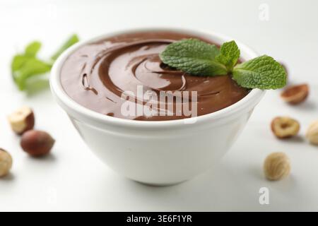 Tasty chocolate paste and hazelnuts on white table, closeup Stock Photo