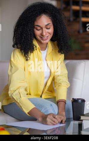 Young woman writing something and looking inspired and focused Stock Photo