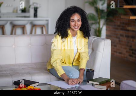 Young woman writing something and looking inspired and focused Stock Photo