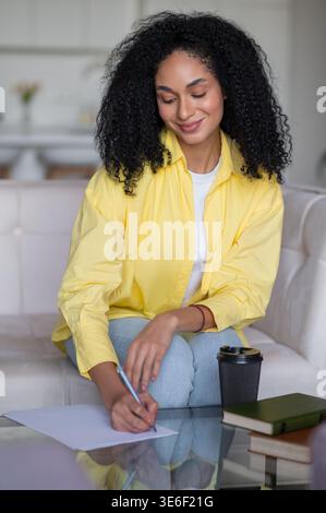 Young woman writing something and looking inspired and focused Stock Photo