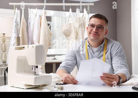 Dressmaker working with sewing pattern at white table in atelier Stock Photo